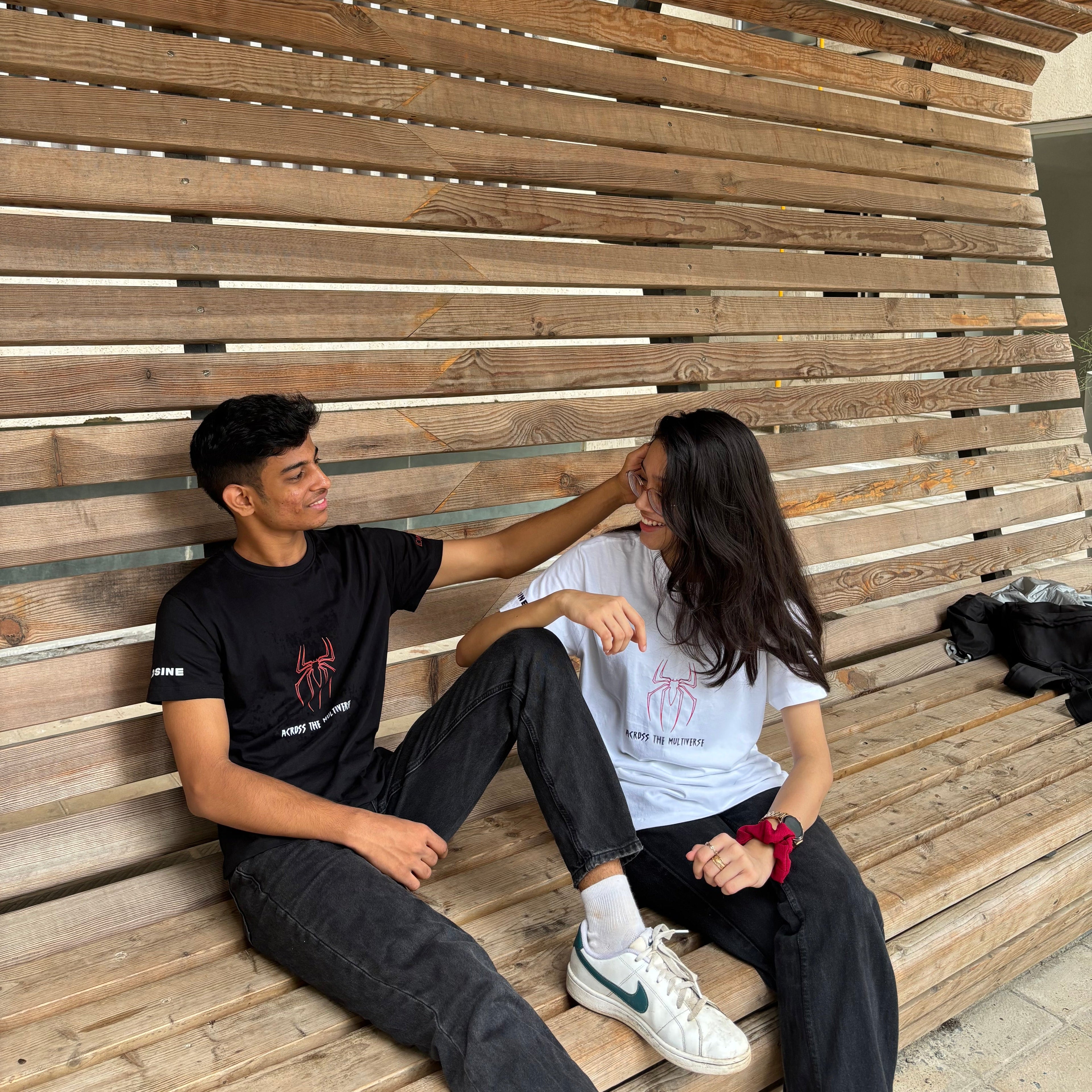 Two people sitting on a wooden bench with a slatted design.