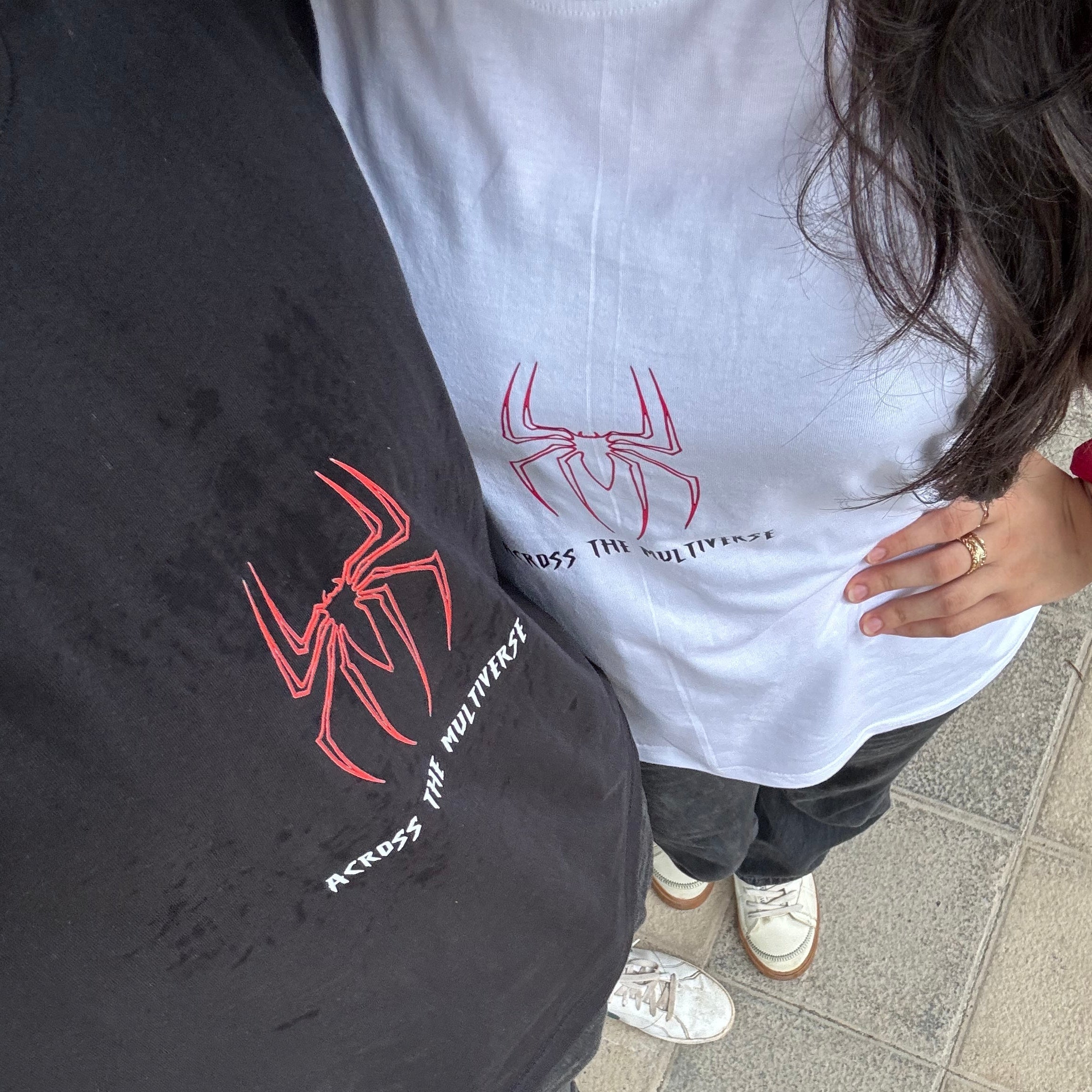 Two people wearing shirts with spider logos on a sidewalk.