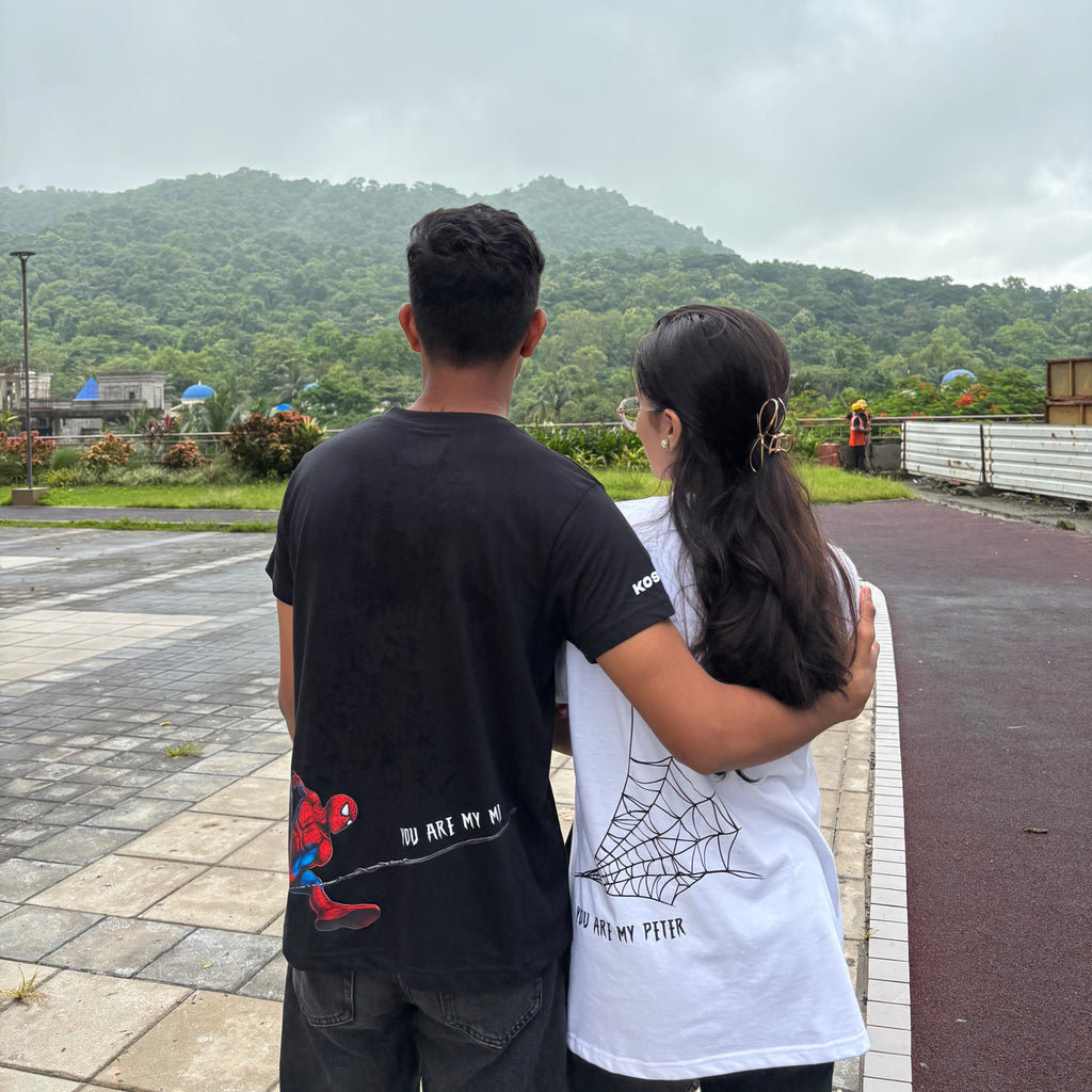 Two people embracing with a scenic view of mountains and clouds in the background.