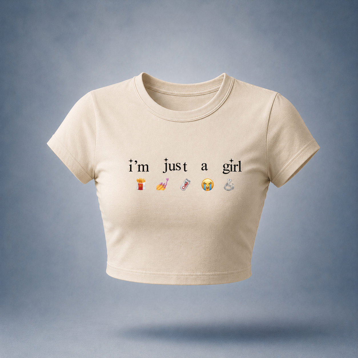 Off-white / Beige crop top with text 'I'm just a girl' and emojis on a bluish white background