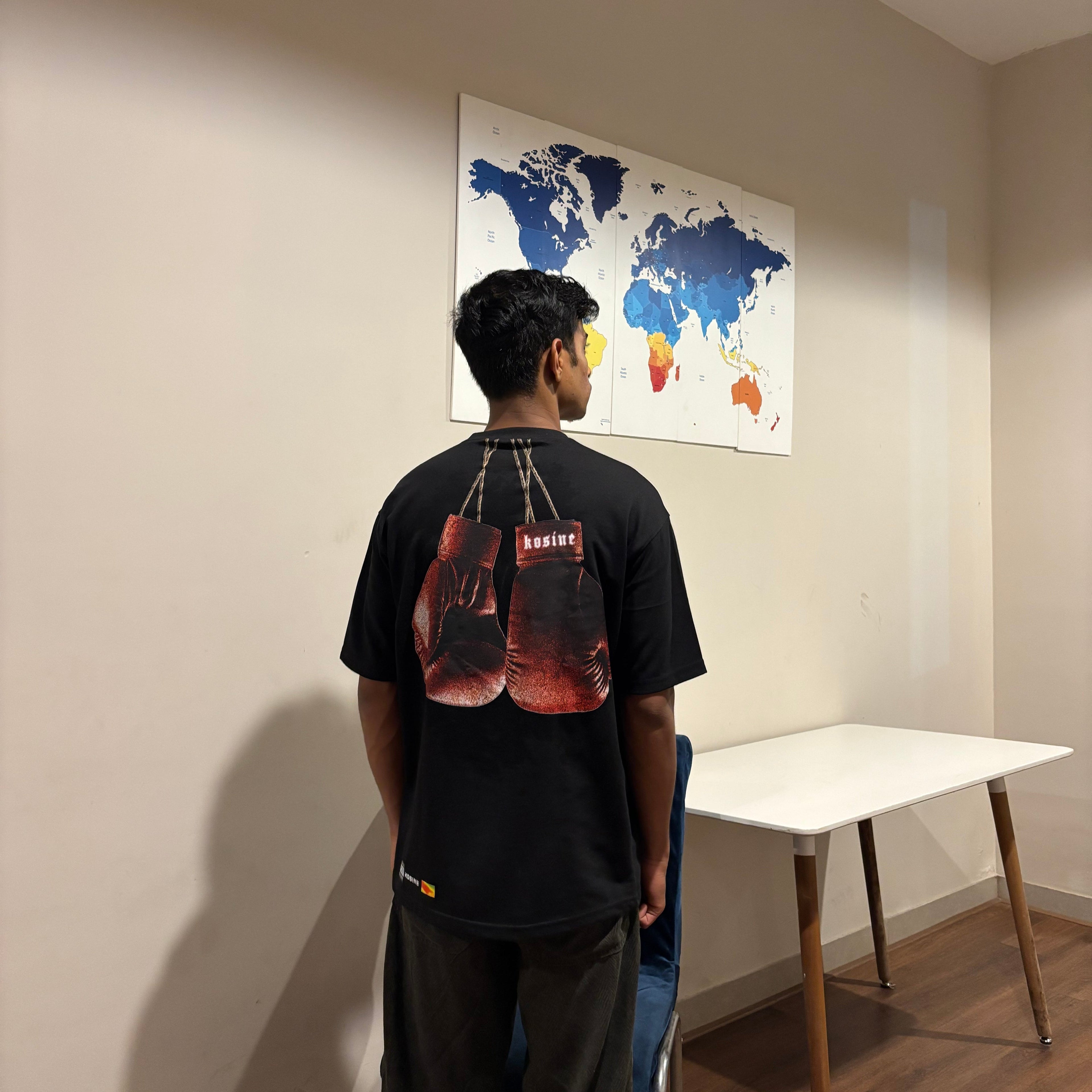 Person standing in a room looking at a world map on the wall.