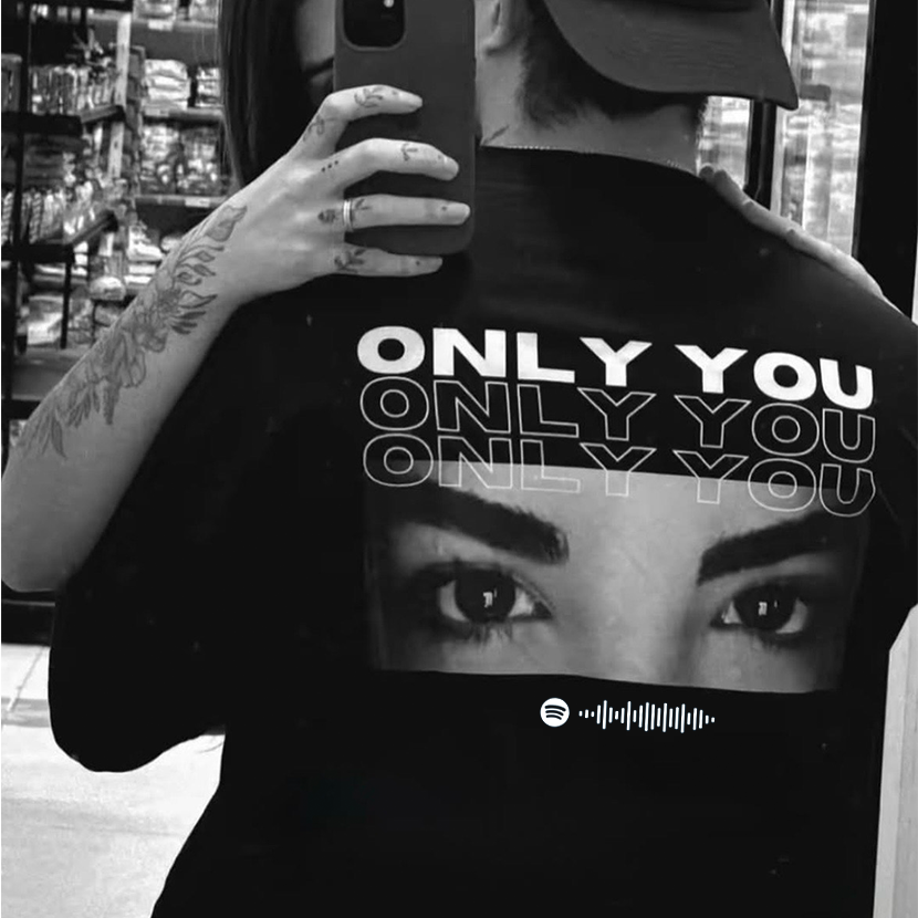 Person wearing a black t-shirt with 'ONLY YOU' text and a graphic of eyes, standing in a store.