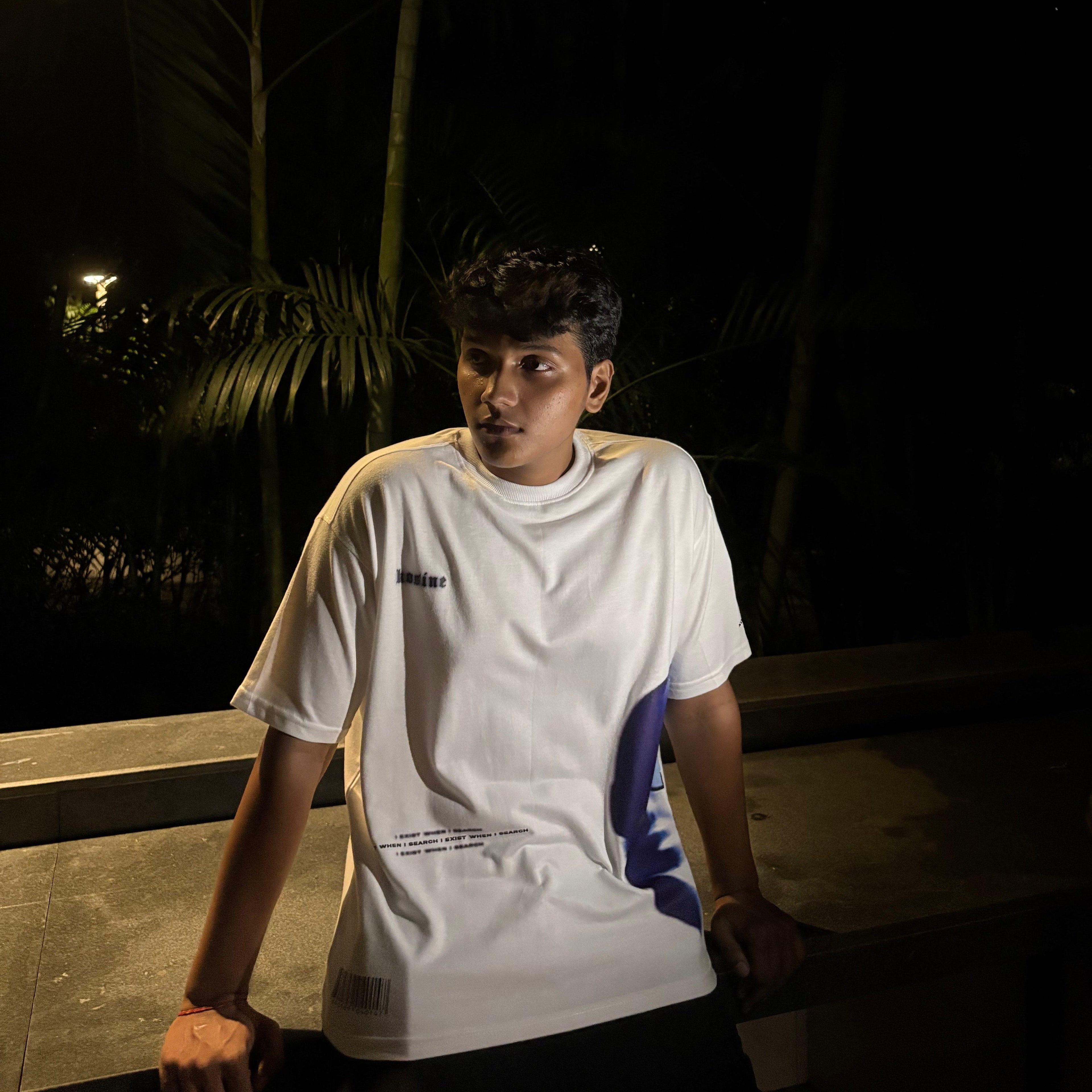 Person wearing a white shirt with a logo in a dark setting