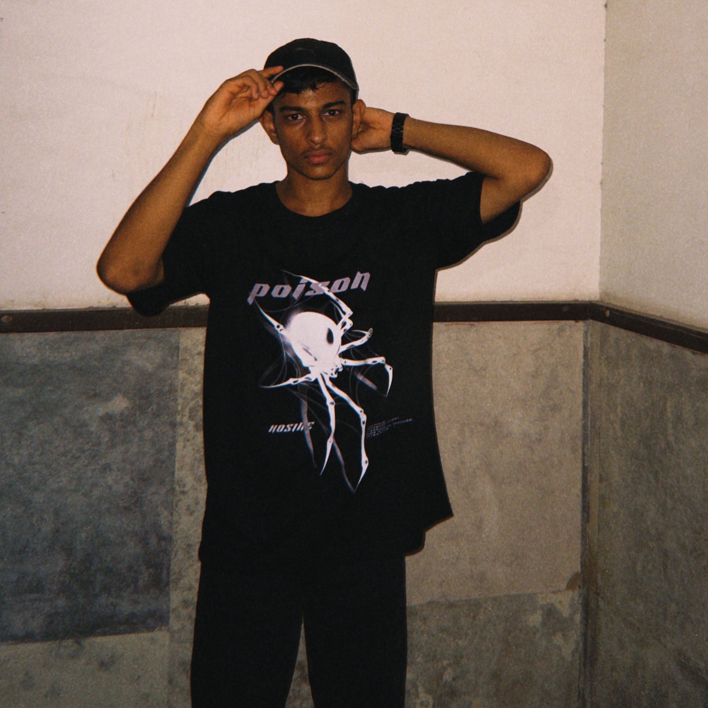 Person wearing a black t-shirt with a graphic design, standing against a plain wall.